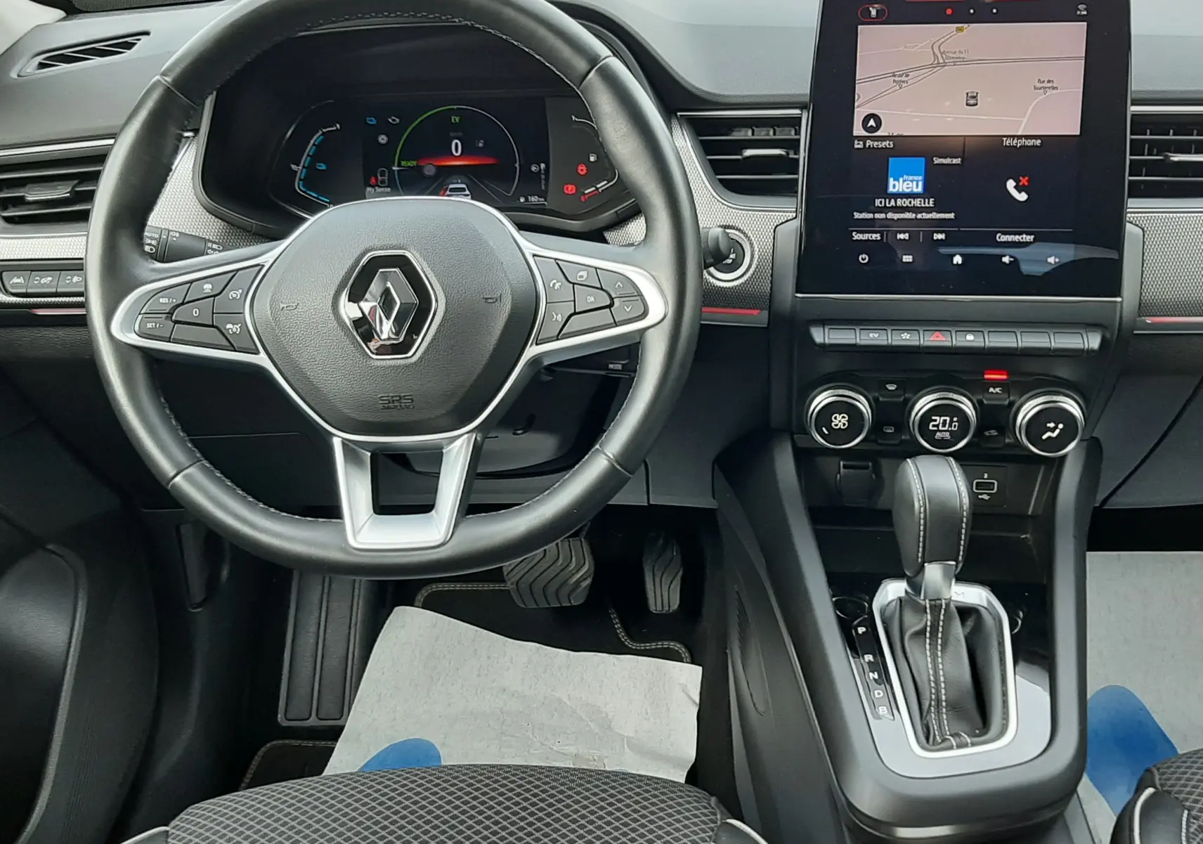 Vue intérieure du tableau de bord et volant Renault Arkana 1.6 E-TECH 145 Intens avec écran tactile et levier de boîte auto.
