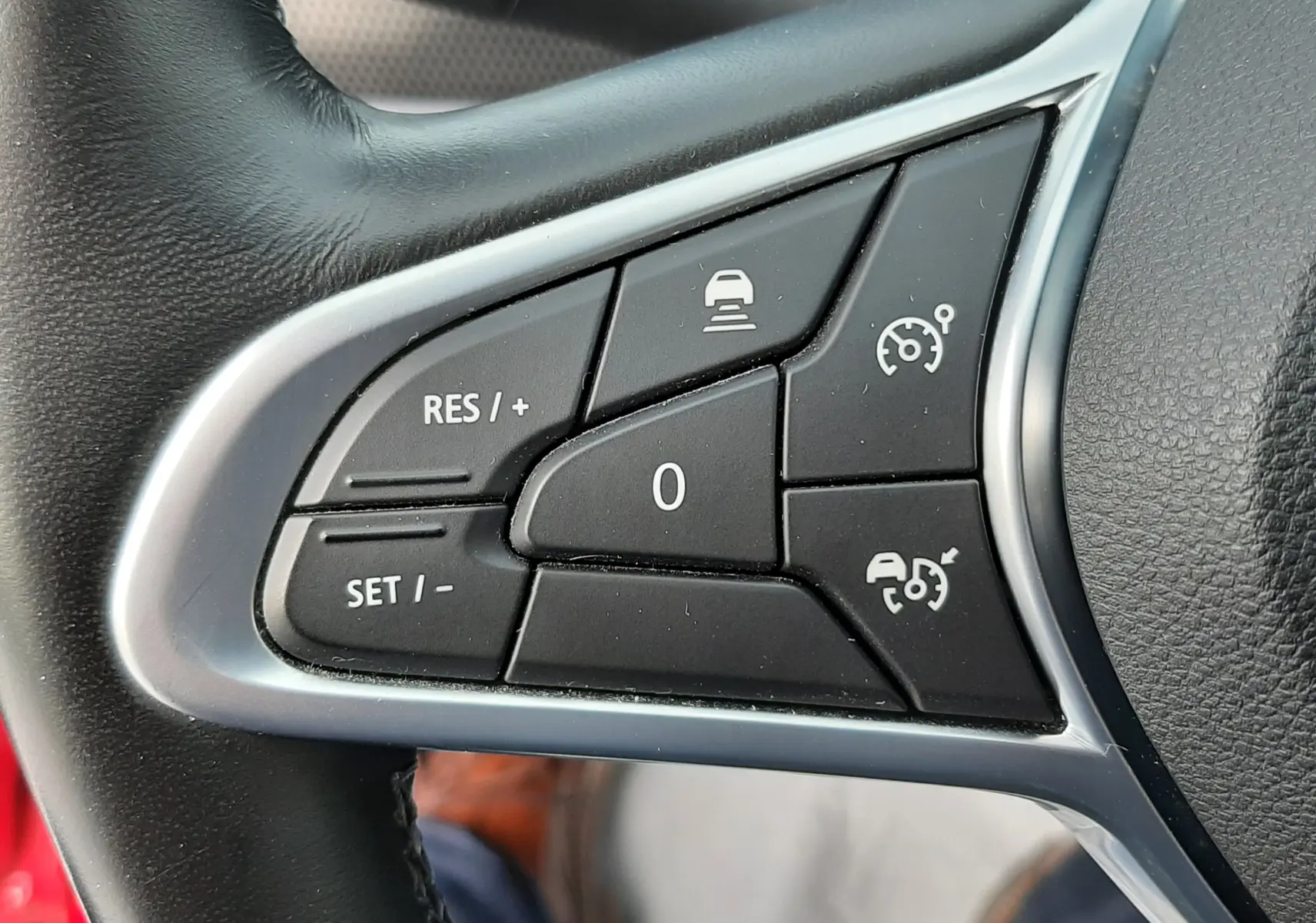 Gros plan sur les commandes de régulateur de vitesse au volant noir du Renault Arkana rouge Flame, version 2021.