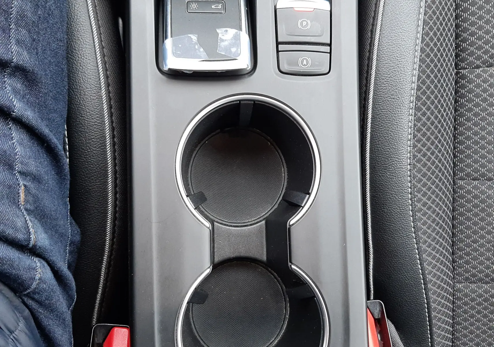 Vue plongeante sur la console centrale noire du Renault Arkana 1.6 E-TECH avec porte-gobelets et commandes électroniques.