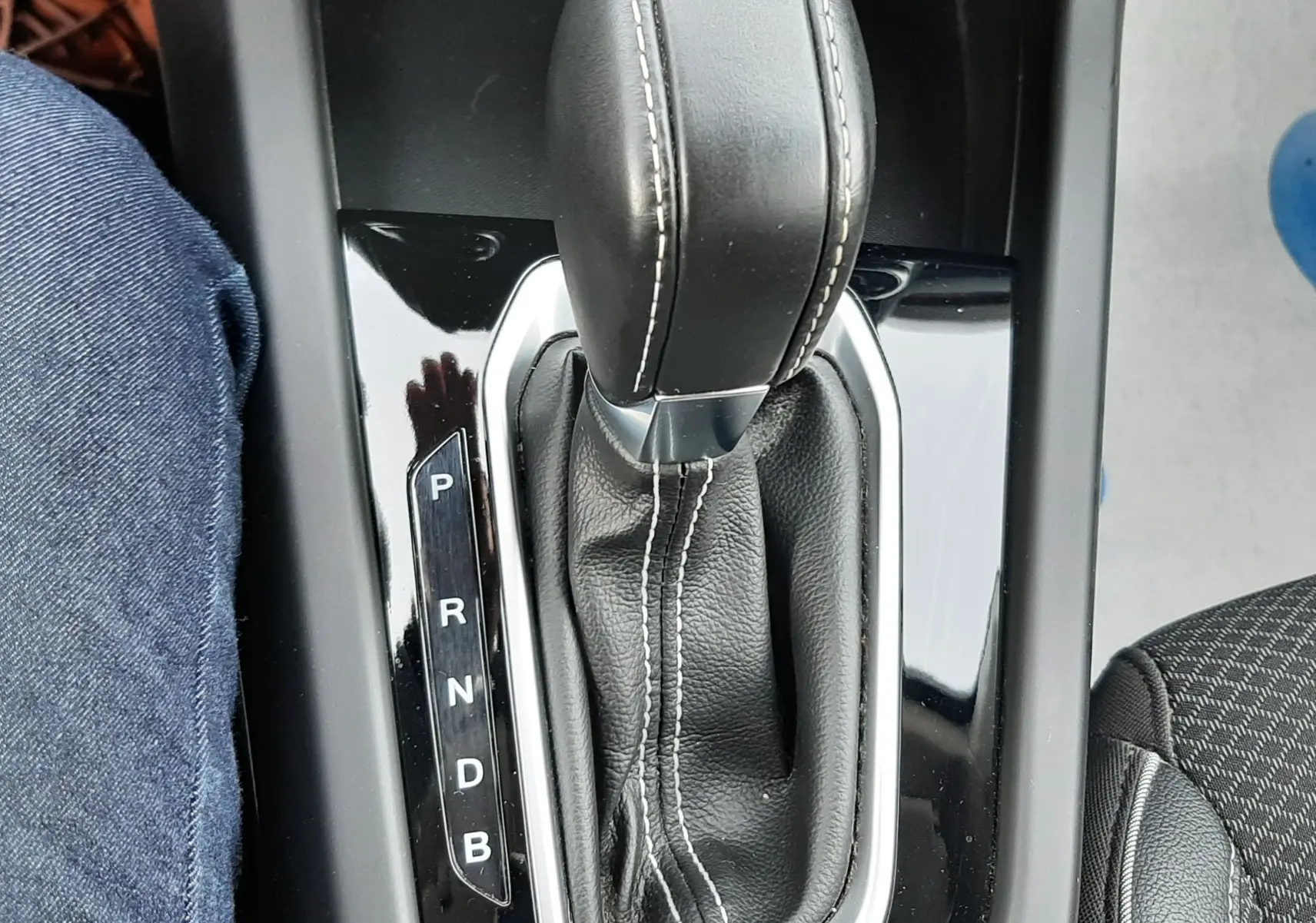 Le levier de vitesses automatique noir avec surpiqûres blanches de la Renault Arkana 1.6 E-TECH 145 Intens, vue plongeante.