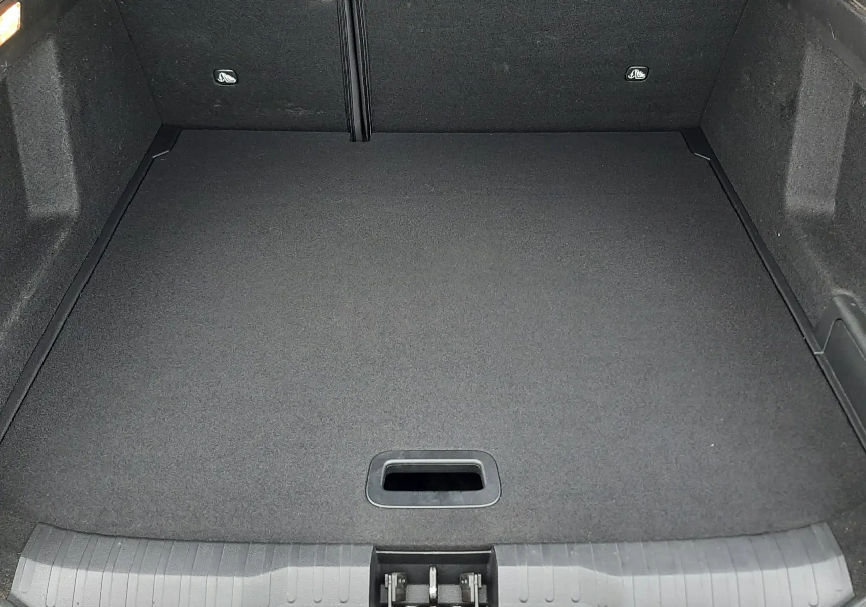 Coffre vide vu de l'arrière d'un Renault Arkana 1.6 E-TECH 145 Intens rouge Flame, revêtement noir uniforme.