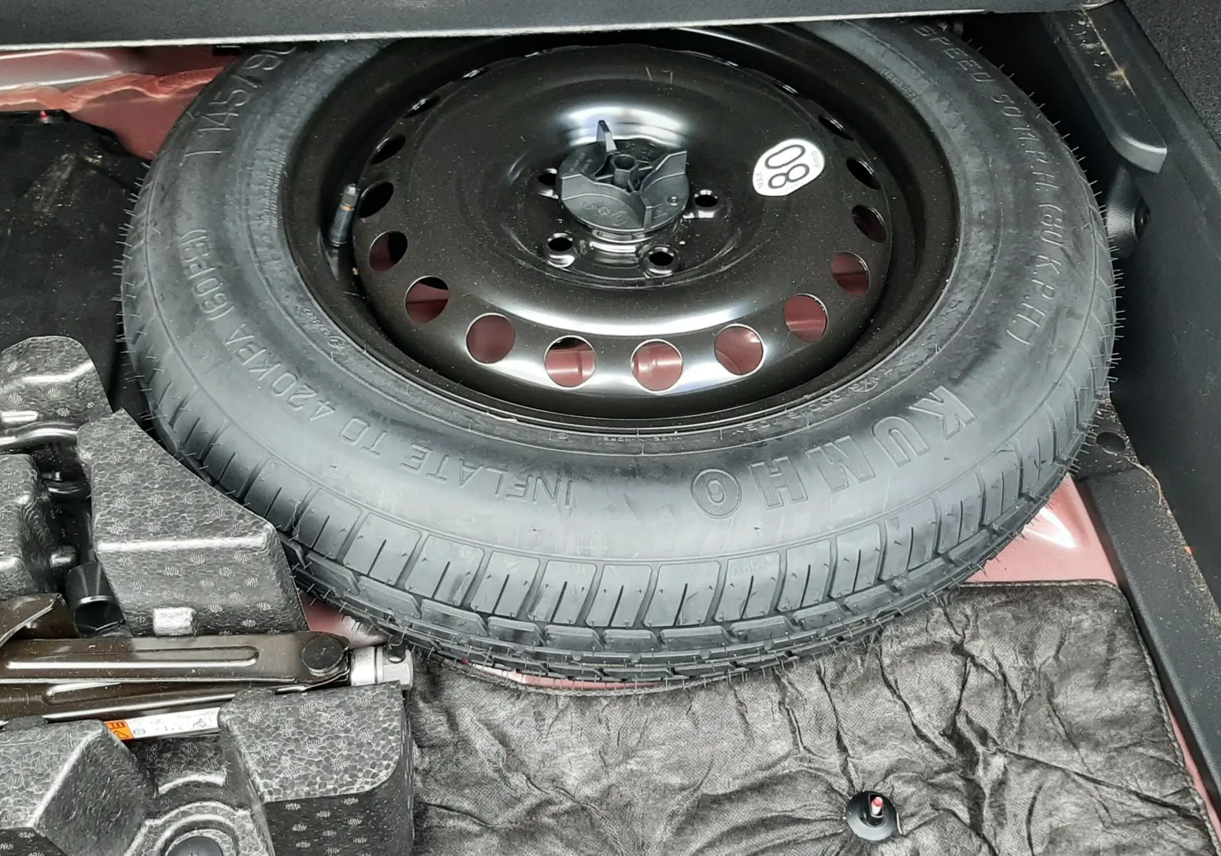 Roue de secours noire et cric dans le coffre d'une Renault Arkana rouge Flame 2021 hybride essence.