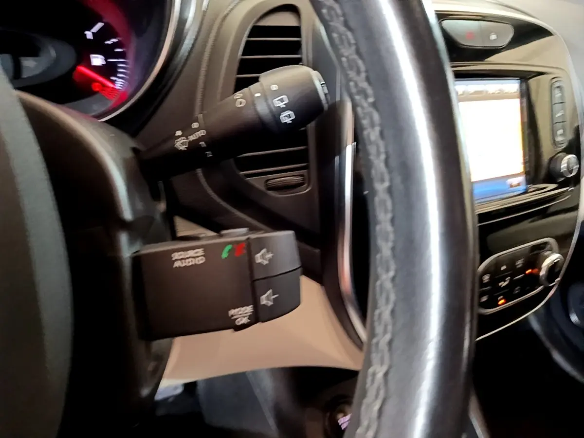 Vue rapprochée du volant cuir et du tableau de bord noir du Renault Captur Intens 2019 avec commandes audio au volant.