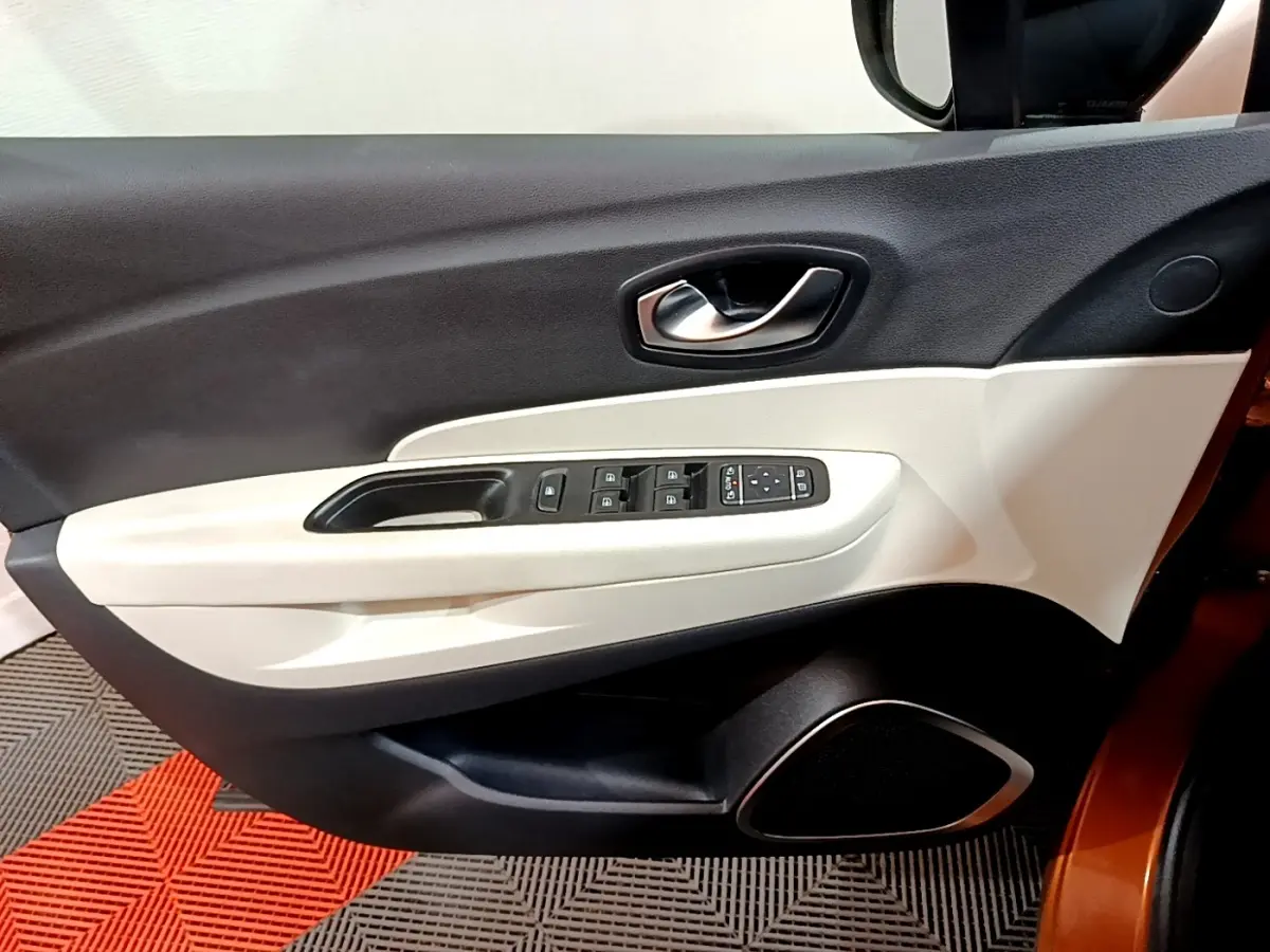 Intérieur côté gauche de la porte avant d'un Renault Captur orange, avec commandes électriques et habillage bicolore noir et beige.