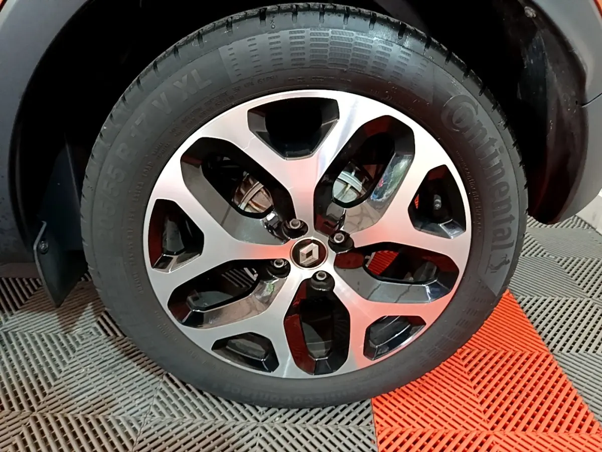 Gros plan sur la jante alliage noire et argentée du Renault Captur orange, avec logo Renault au centre.