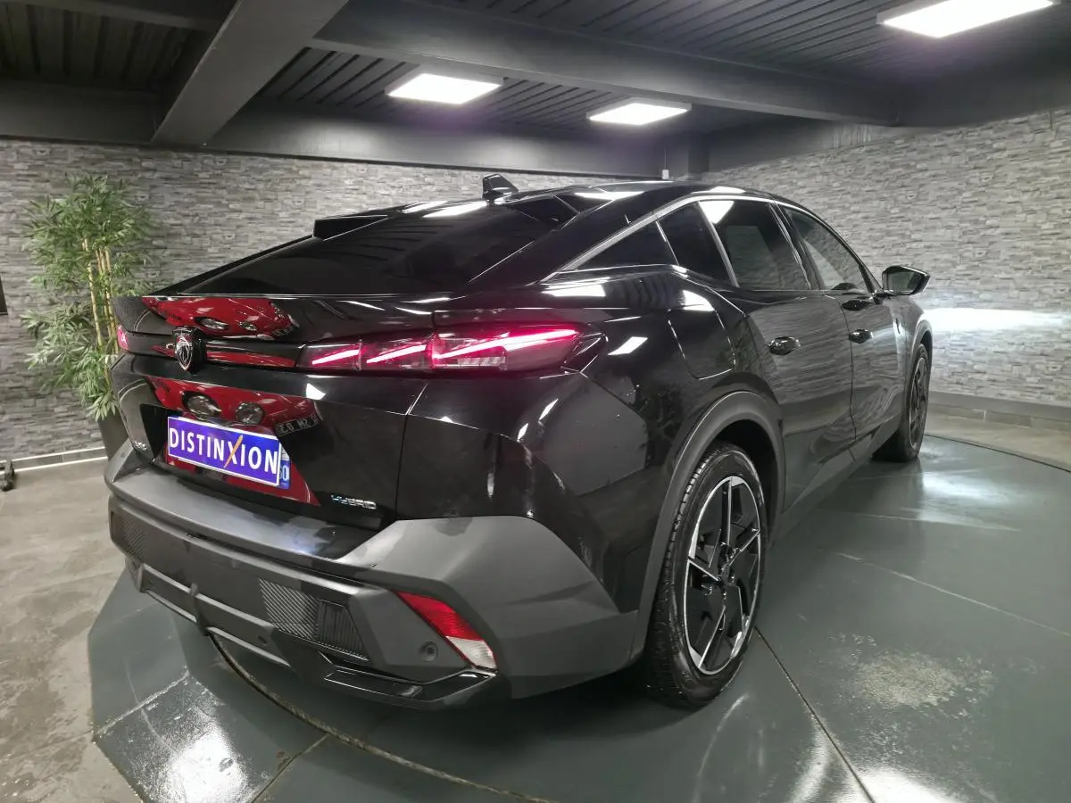 Vue 3/4 arrière droite d'une Peugeot 408 noire avec feux arrière LED distinctifs dans un showroom.