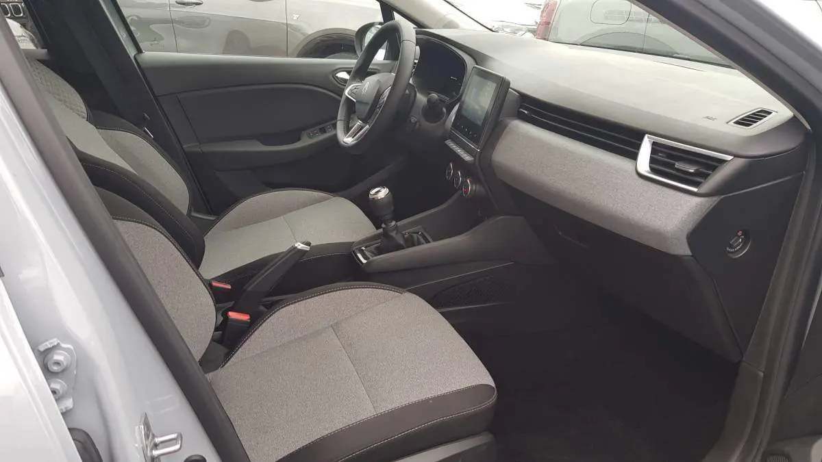 Vue intérieure côté conducteur de la Renault Clio V dCi 100 Evolution 2025, sièges gris et tableau de bord moderne.