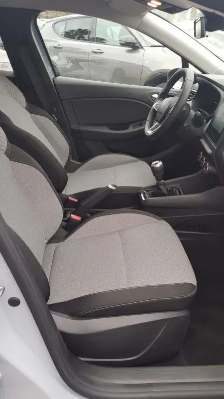 Vue intérieure côté conducteur de la Renault Clio gris 2025 avec boîte manuelle et sièges tissu clair.