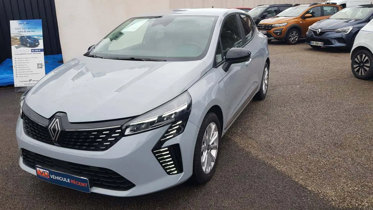 Renault Clio gris 2025 vue 3/4 avant droit, avec feux LED distinctifs et calandre noire brillante.