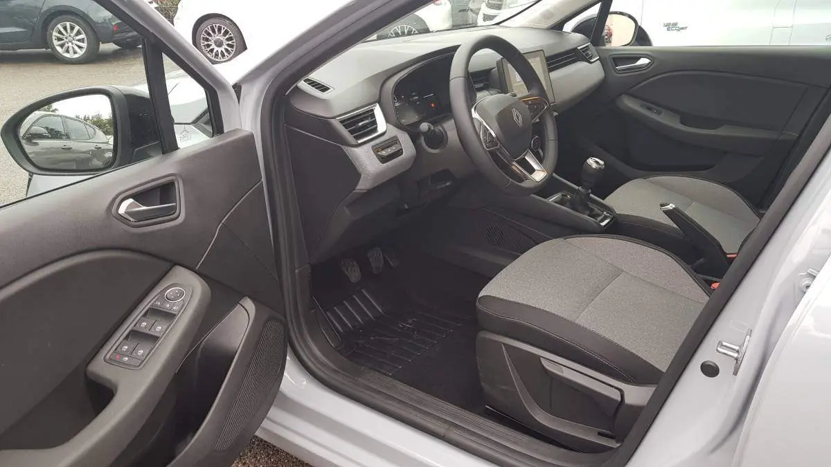 Intérieur côté conducteur d'une Renault Clio gris 2025, avec tableau de bord moderne et boîte manuelle visible.