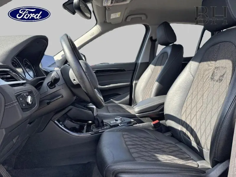 Vue intérieure côté conducteur du BMW X1 xDrive25eA 2021, sièges cuir et tissu noirs avec motifs géométriques.