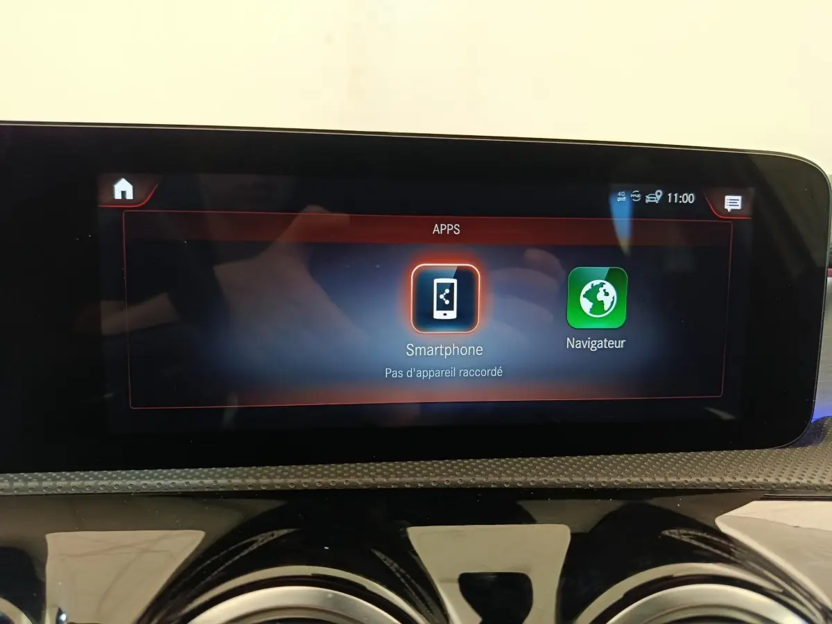Écran tactile central affichant les applications smartphone et navigateur dans une Mercedes Classe A blanche.
