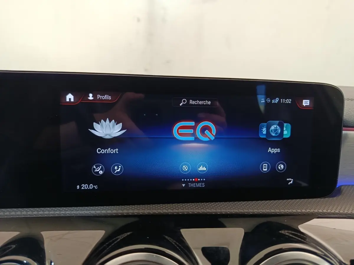 Écran tactile central affichant le menu EQ dans l'habitacle d'une Mercedes Classe A blanche, version AMG Line.