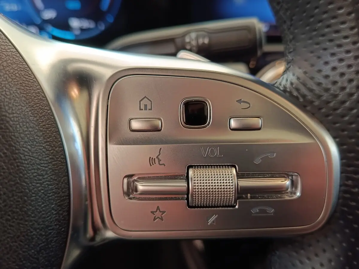 Gros plan sur les commandes en aluminium et cuir du volant multifonctions du Mercedes Classe A blanc, version AMG Line.