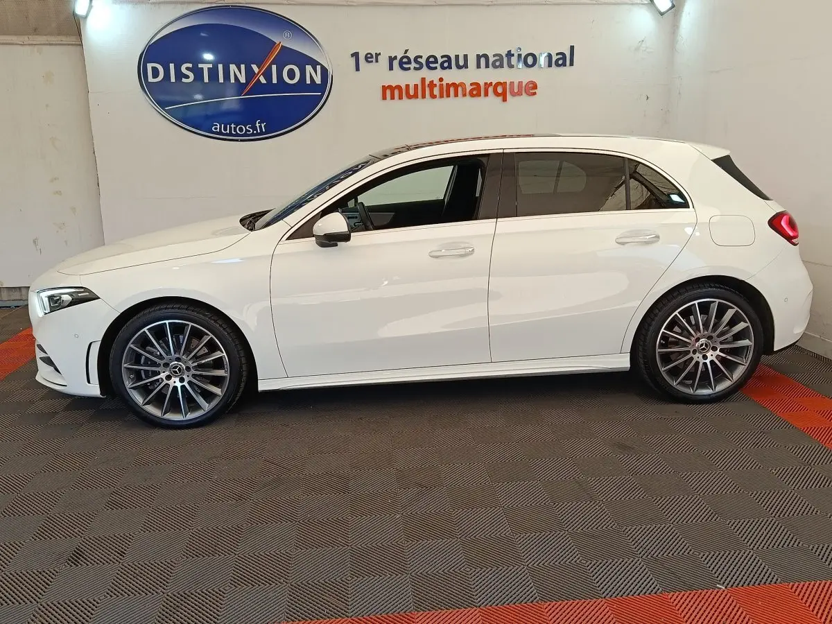 Vue de profil côté gauche d'une Mercedes Classe A blanche A 250 e AMG Line avec jantes alliage et vitres teintées.