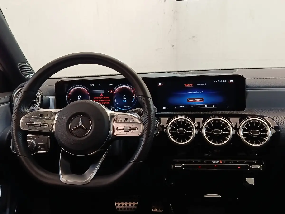 Vue intérieure du tableau de bord et volant cuir alu multifonctions de la Mercedes Classe A 250 e AMG Line blanche de 2021.