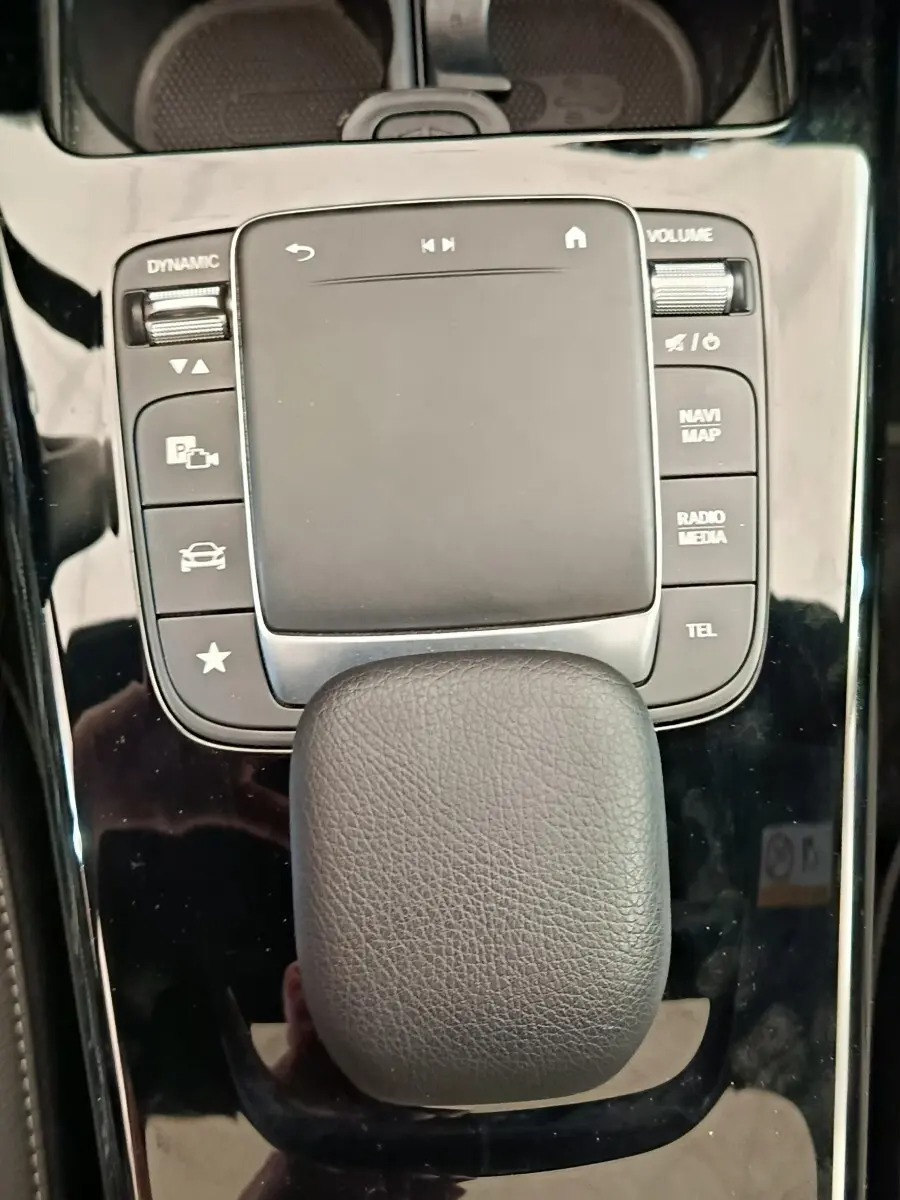 Vue rapprochée du pavé tactile noir et des boutons de commande sur la console centrale brillante d'une Mercedes Classe A blanche.
