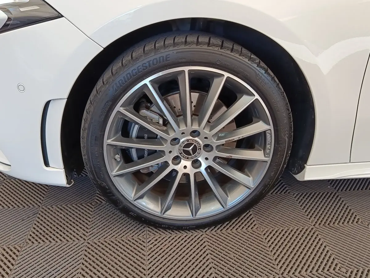Gros plan sur la roue avant droite argentée AMG d'une Mercedes Classe A blanche, avec pneu Bridgestone visible.