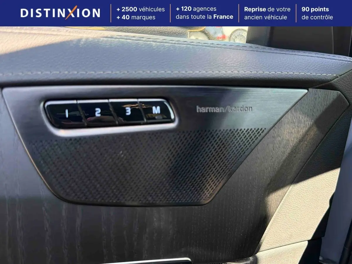 Détail intérieur montrant la porte côté conducteur du Volvo XC90 gris avec haut-parleur Harman Kardon et commandes mémoire sièges.