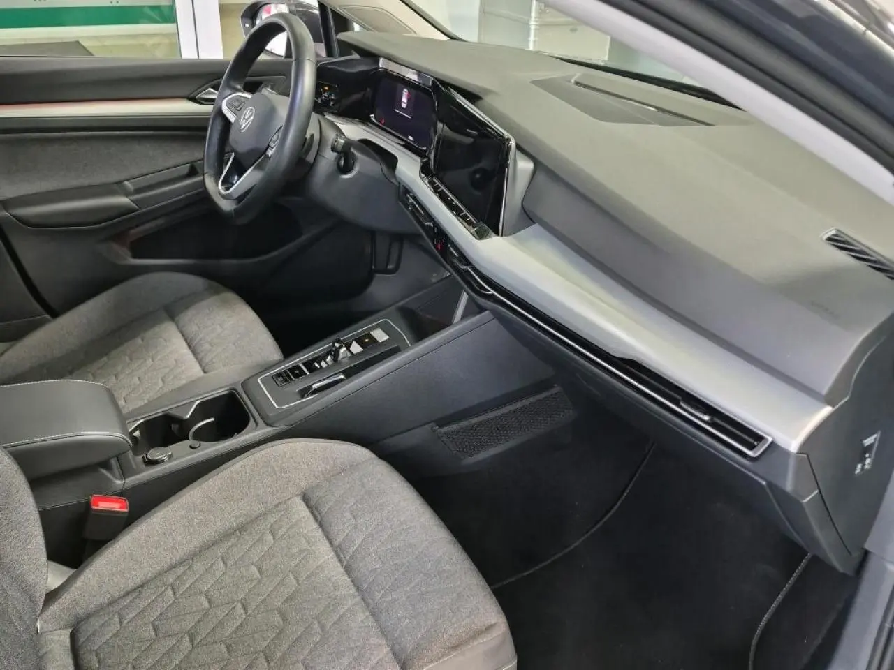 Intérieur avant droit de la Volkswagen Golf 8 gris Urano, avec tableau de bord numérique et sièges tissu gris.