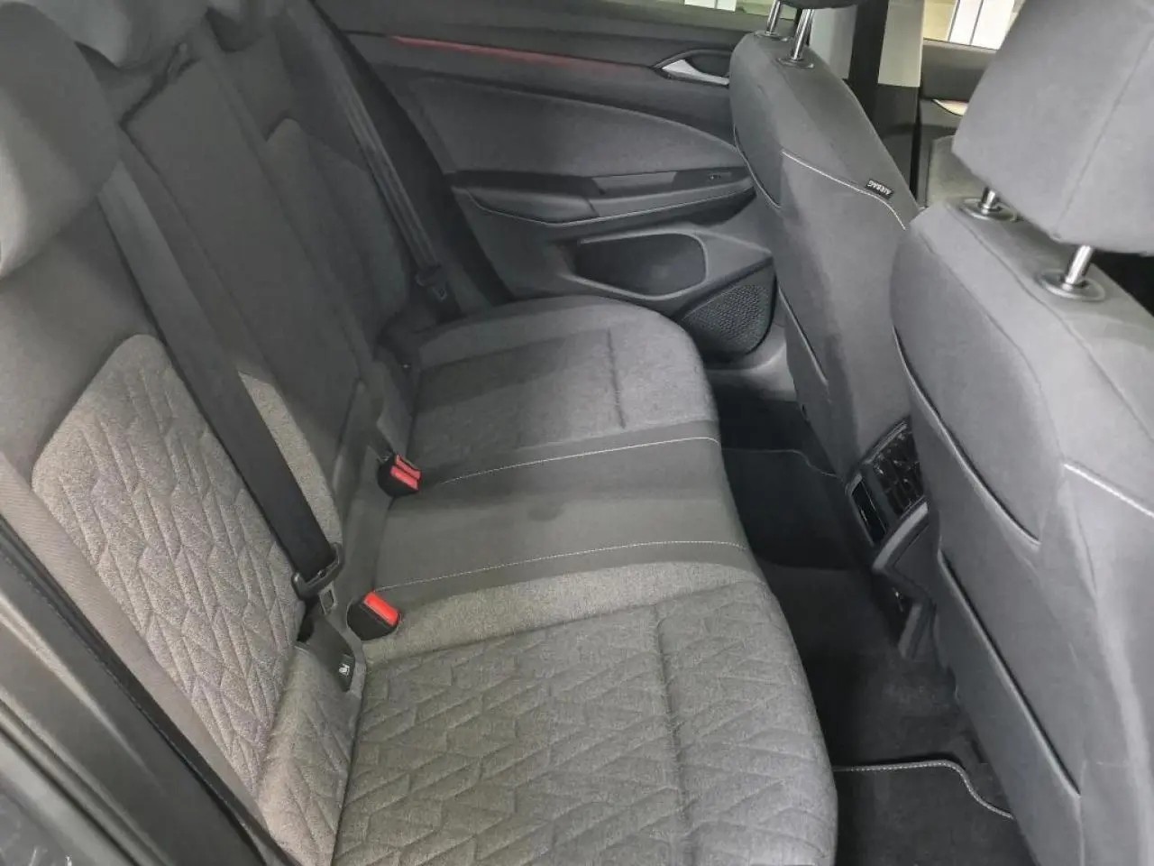 Vue côté droit de la banquette arrière grise de la Volkswagen Golf 8 avec ceintures de sécurité et appuis-tête.