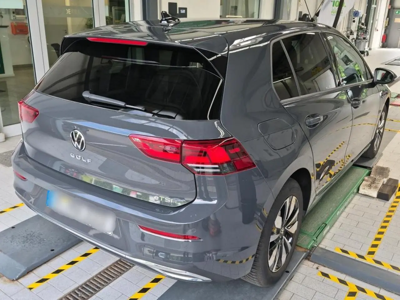 Vue 3/4 arrière droite d'une Volkswagen Golf 8 gris Urano avec feux arrière LED et vitres teintées.