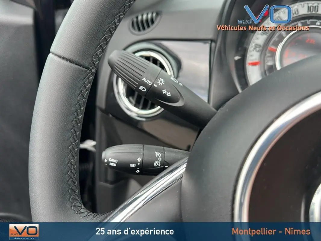 Gros plan sur le volant et les commandes de clignotants d'une FIAT 500C noire 2024 avec tableau de bord visible.