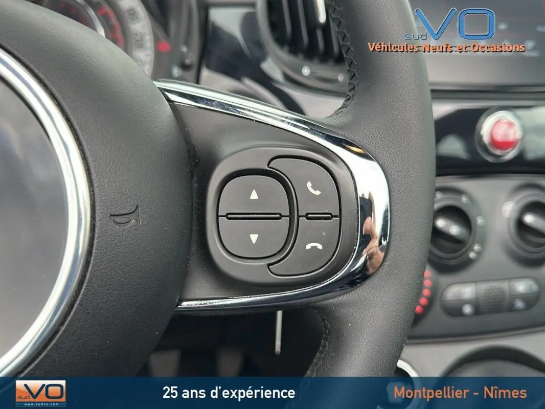Gros plan sur les commandes du volant d'une FIAT 500C noire 2024, mettant en valeur les boutons de gestion d'appels et volume.