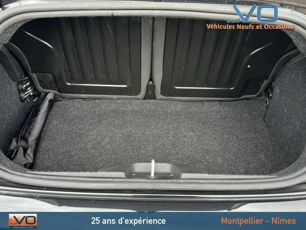 Coffre ouvert d'une FIAT 500C noire 2024, vue arrière montrant la roue de secours rangée sur le côté gauche.