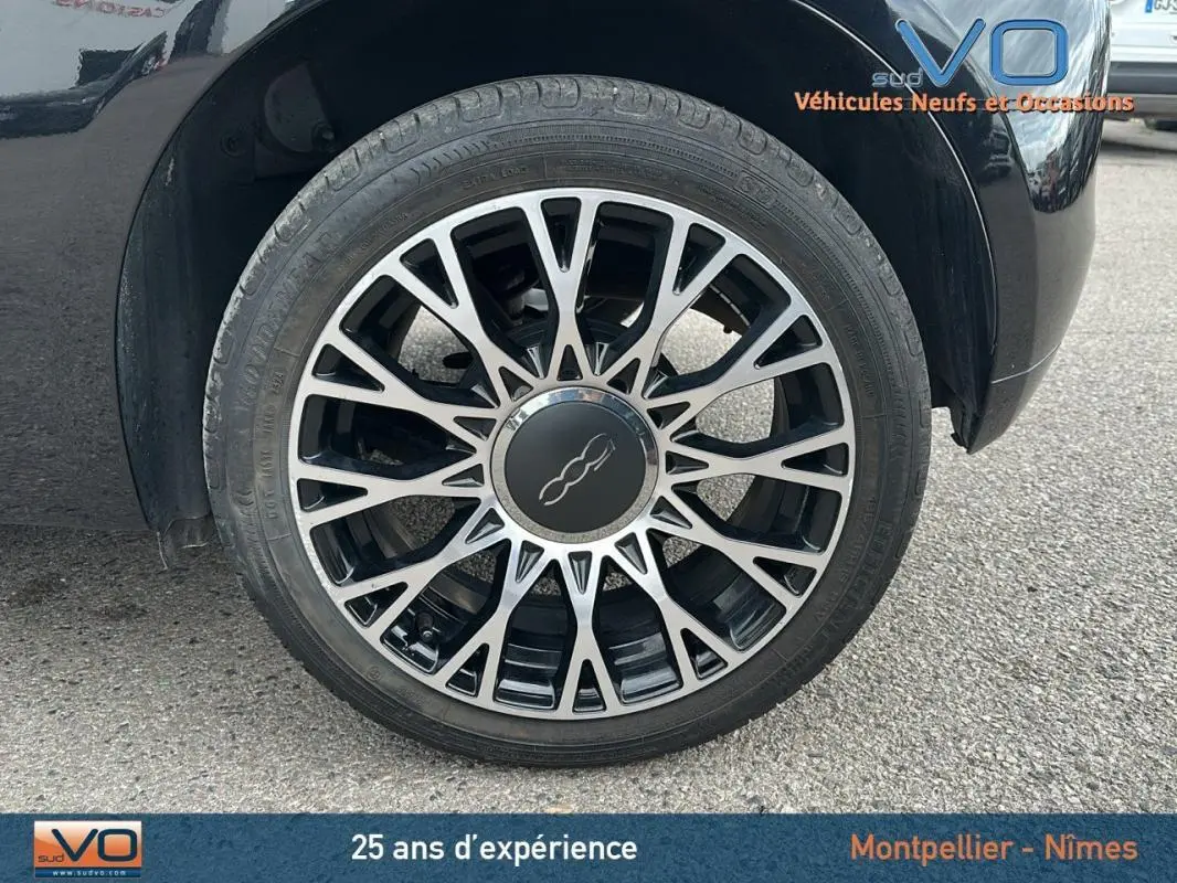 Gros plan sur la roue avant gauche noire de la FIAT 500C 2024 avec jante en alliage au design étoilé.