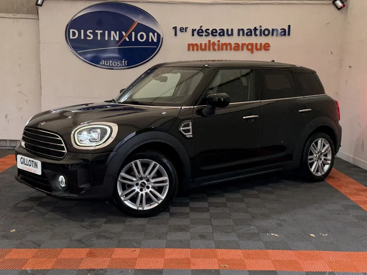 MINI Countryman noir vue de profil côté gauche en intérieur, avec jantes alliage et phares LED allumés.