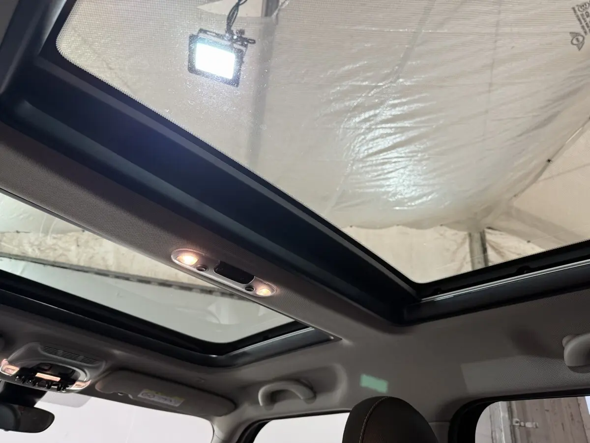 Toit panoramique ouvert vu de l'intérieur sur une MINI Countryman noire, mettant en valeur la luminosité naturelle.