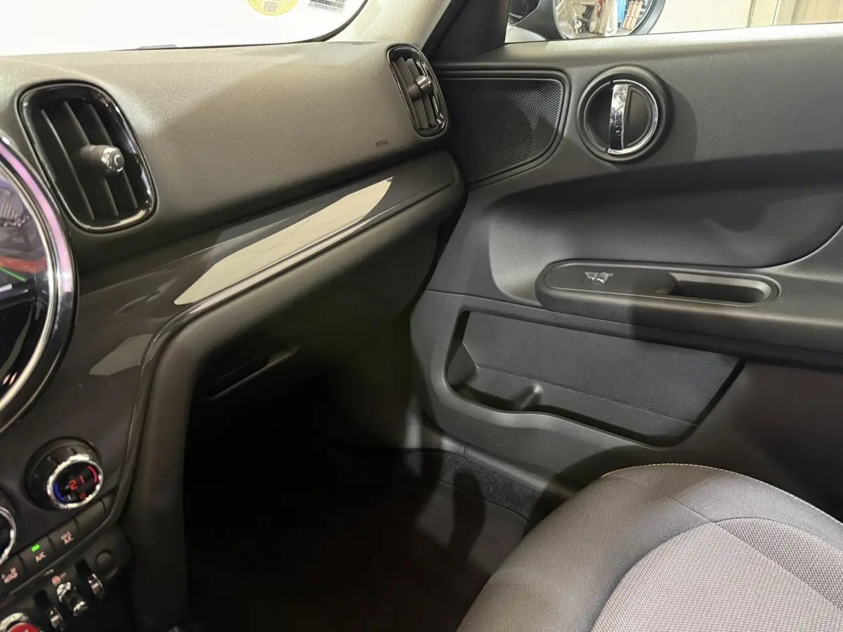 Vue intérieure côté passager du tableau de bord et porte d'une MINI Countryman noire, finition Business Design 2020.