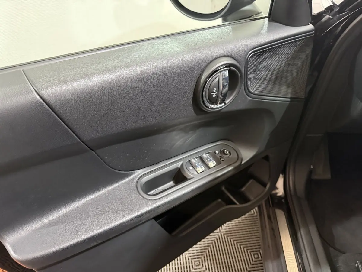 Vue rapprochée de la porte avant gauche noire d'une MINI Countryman 2020, avec commandes de vitres et serrure intégrée.