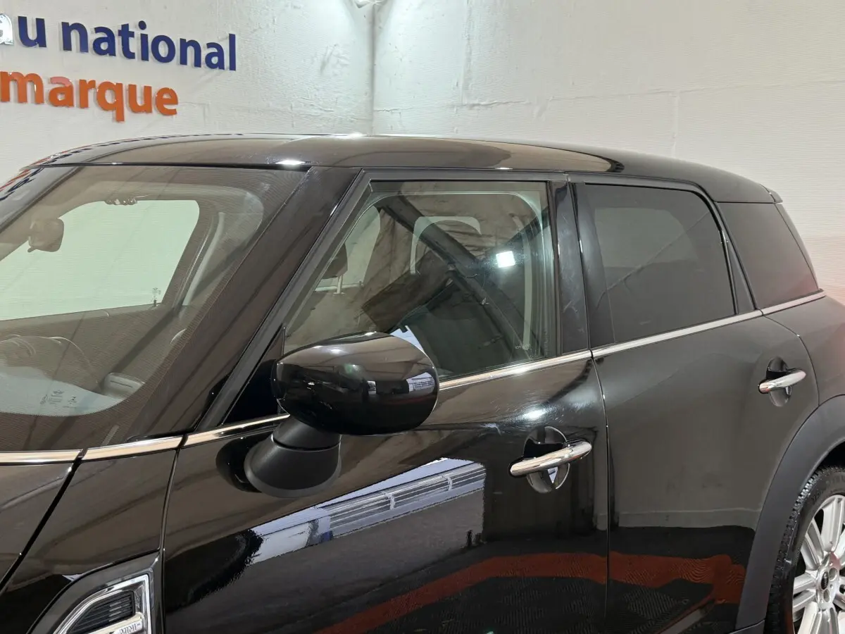 Vue côté gauche rapprochée d'une MINI COUNTRYMAN noire 2020 avec rétroviseur et poignées chromés visibles.