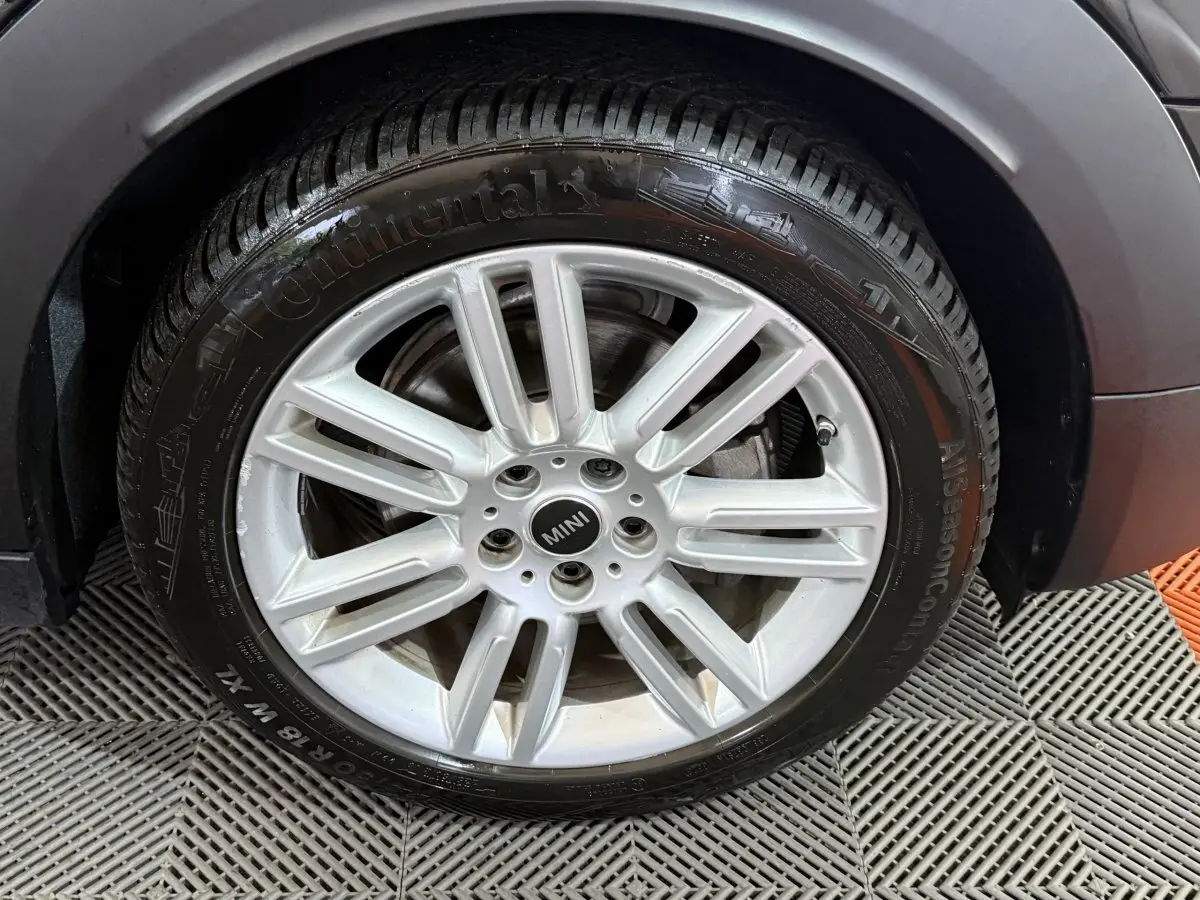 Gros plan sur la roue avant droite avec jante argentée et logo MINI du MINI COUNTRYMAN noir 2020.