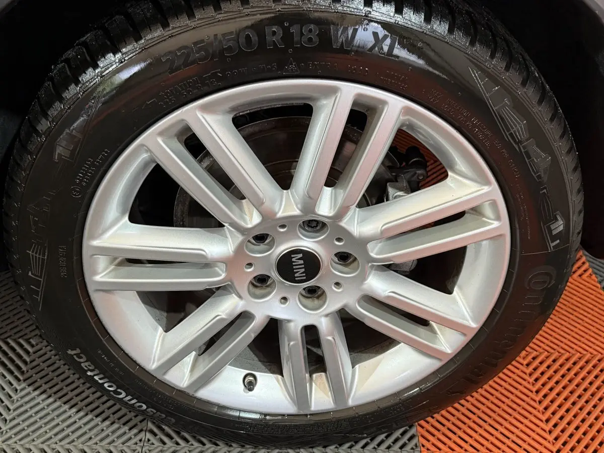 Gros plan sur la jante argentée à dix branches d'une MINI Countryman noire, avec pneu Continental visible.