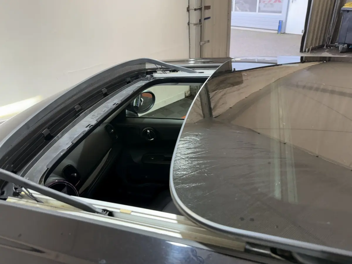 Vue plongeante sur le toit ouvrant panoramique ouvert d'une MINI Countryman noire, montrant l'intérieur côté conducteur.