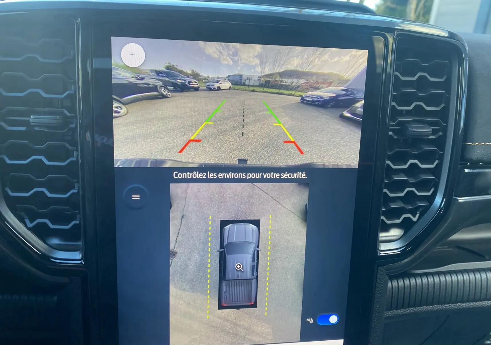 Écran central du Ford Ranger gris carbone 2025 montrant la caméra 360° et l'aide au stationnement vue intérieure.