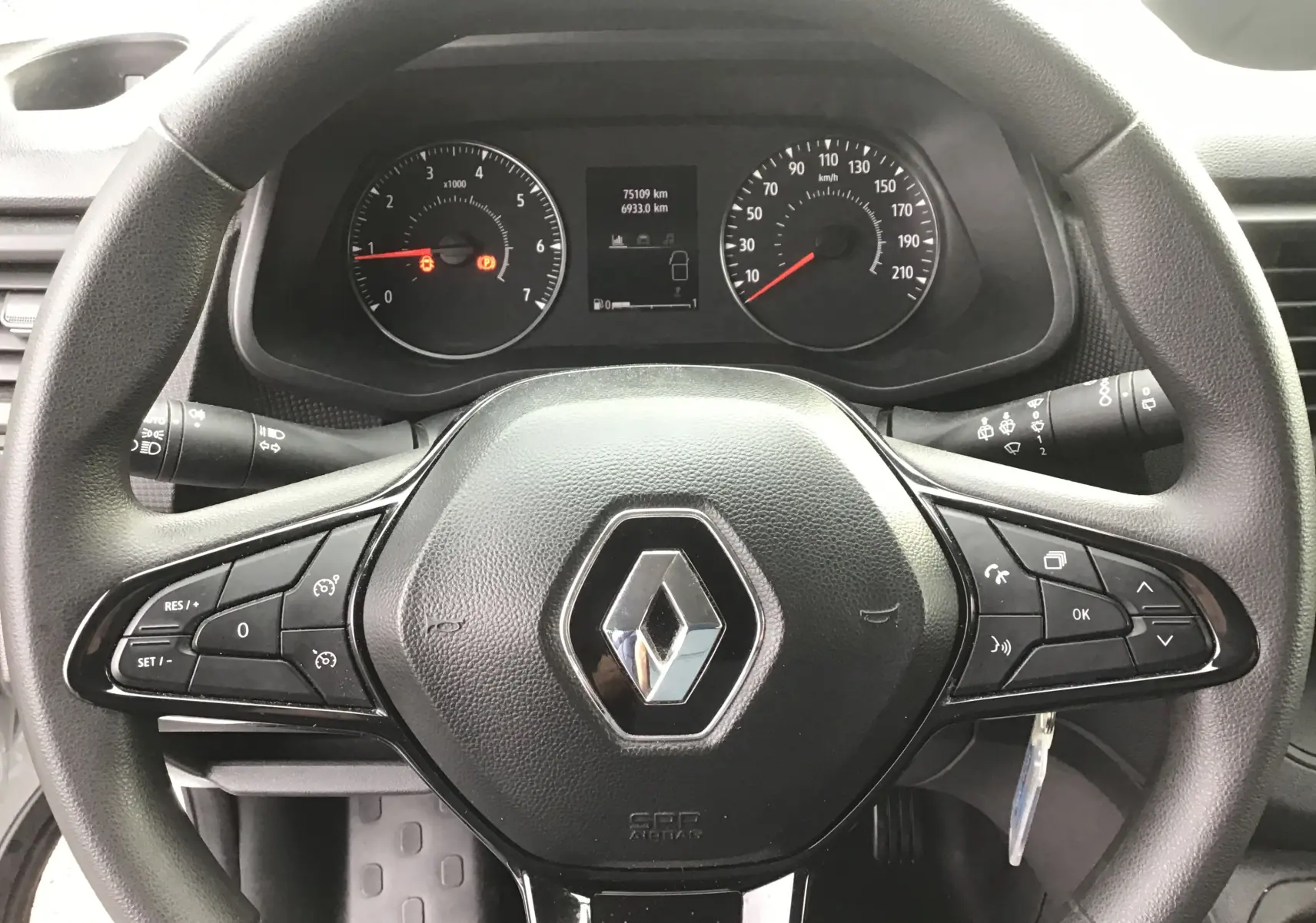 Vue rapprochée du volant noir de Renault Trafic Combi gris Highland, avec commandes intégrées et tableau de bord visible.