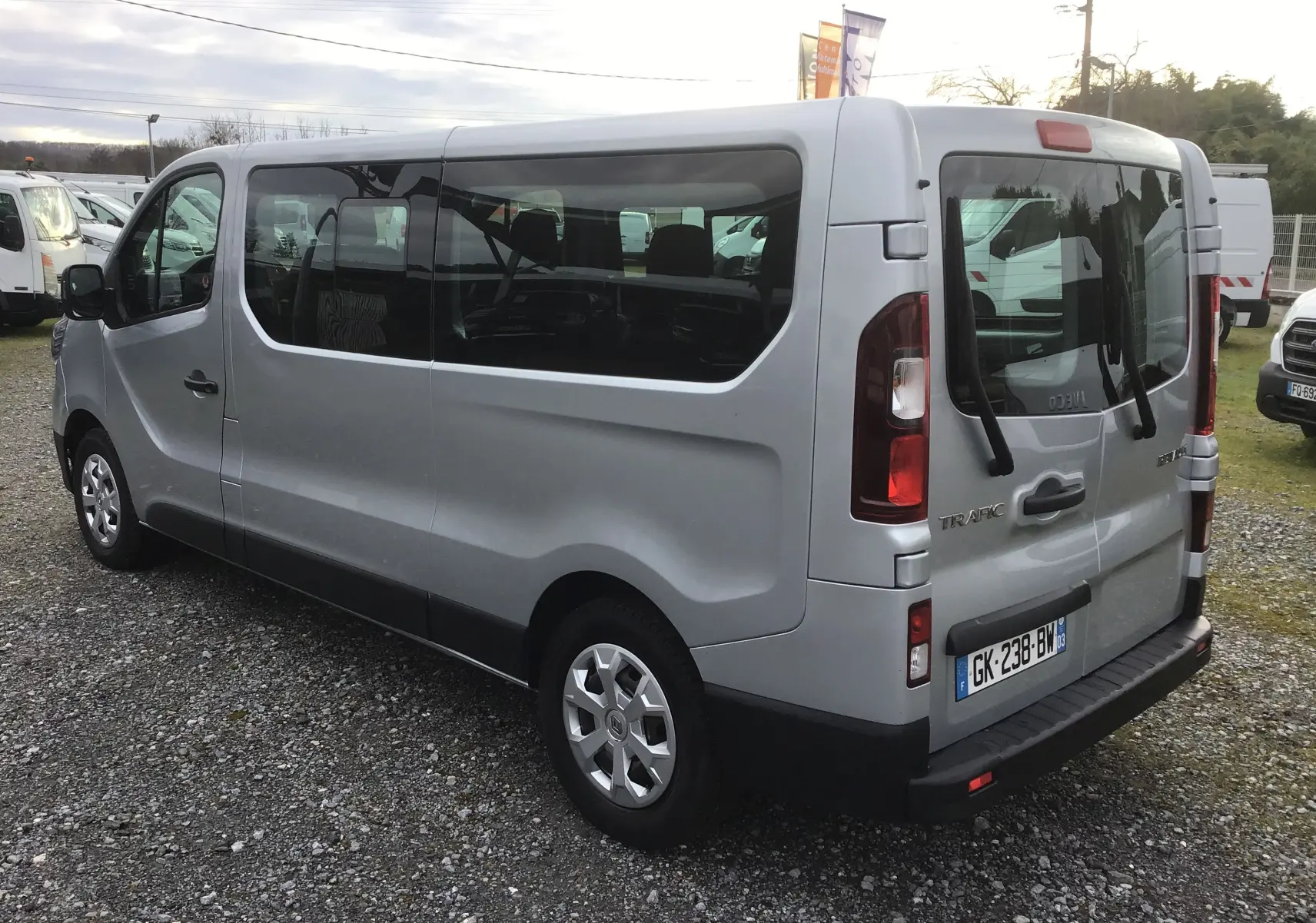 Renault Trafic Combi gris Highland vu en 3/4 arrière droit, avec vitres latérales teintées et porte arrière double.