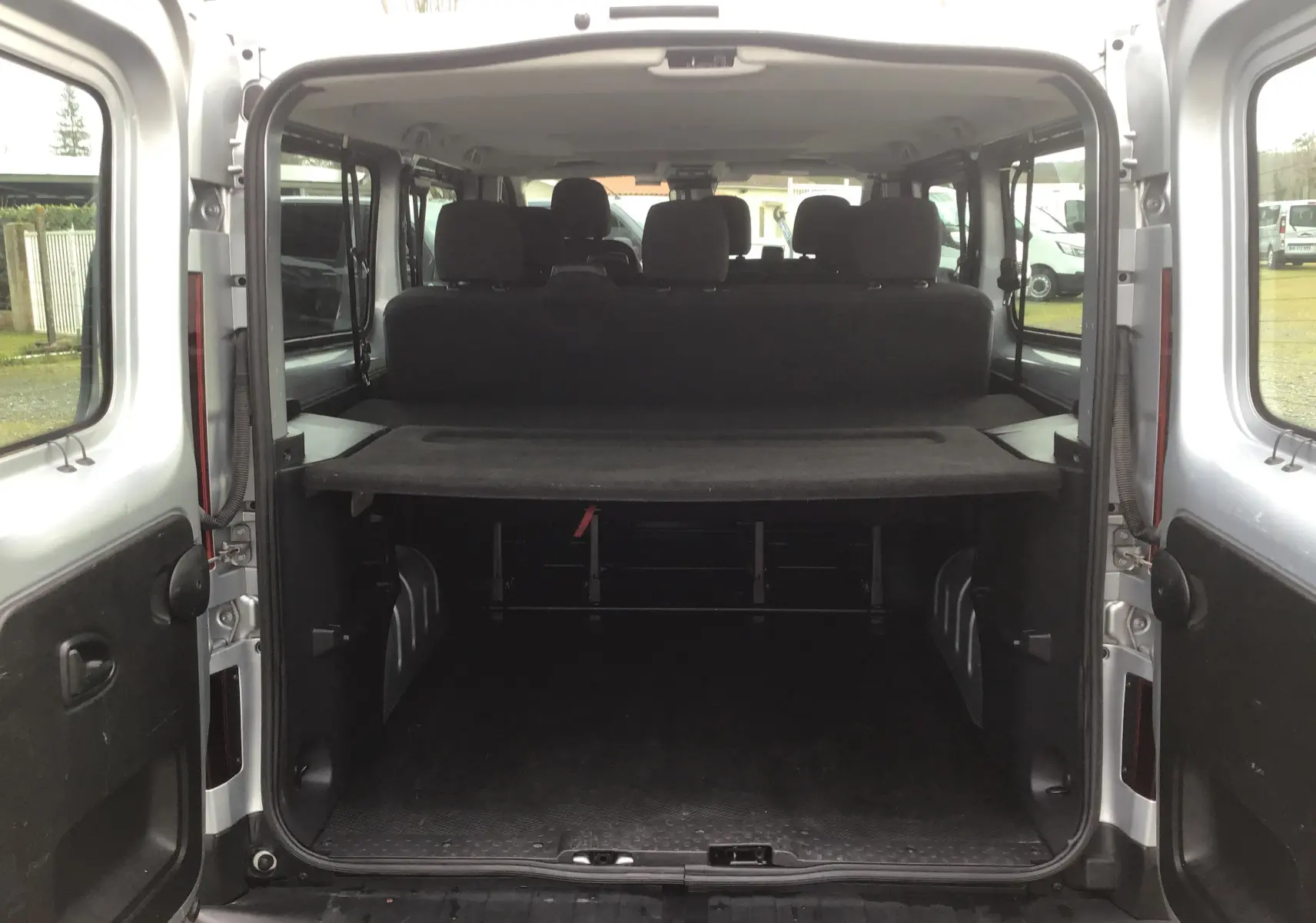 Vue arrière ouverte du Renault Trafic Combi gris Highland montrant l'espace de chargement et les sièges arrière.