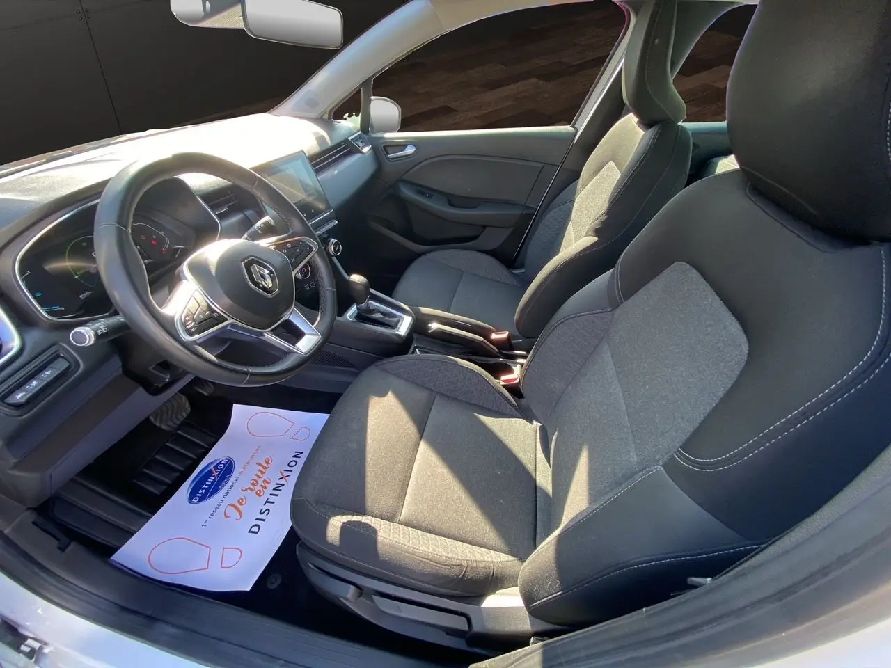 Vue intérieure côté conducteur de la Renault Clio V E-Tech 140 Business, sièges tissu noir et tableau de bord moderne.