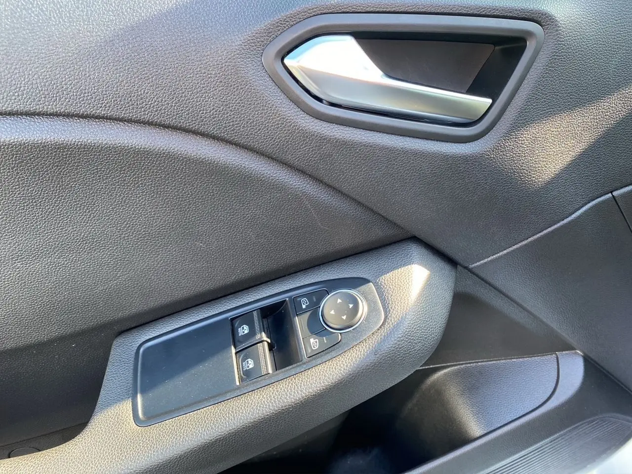 Gros plan sur la commande des vitres et rétroviseurs côté conducteur de la Renault Clio V E-Tech 140 Business en intérieur noir.