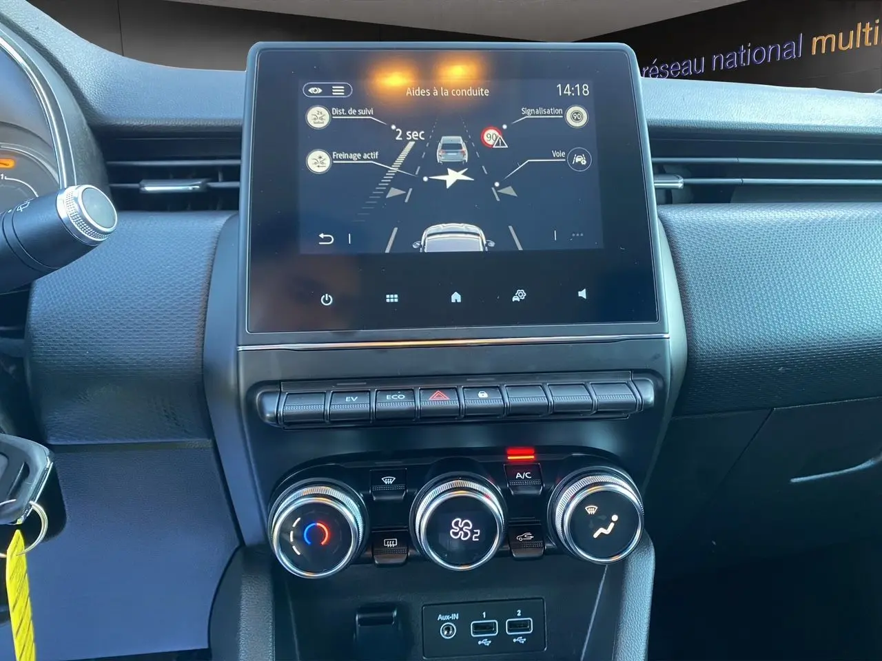 Vue rapprochée du tableau de bord de la Renault Clio V E-Tech 140, avec écran tactile et commandes de climatisation.