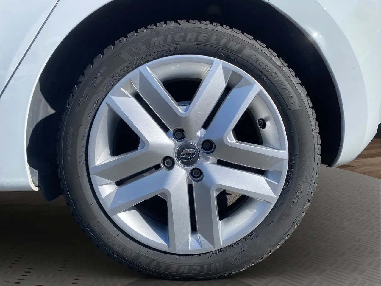 Gros plan sur la roue avant droite d’une Renault Clio V blanche, avec jante alliage argentée et pneu Michelin.