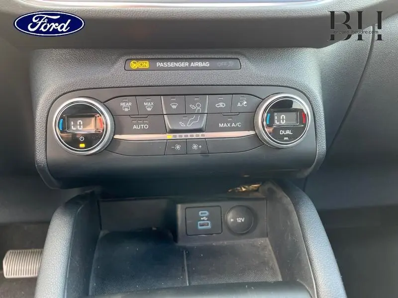 Vue rapprochée de la console centrale du Ford Kuga 2022 montrant les commandes de climatisation bi-zone et prises USB et 12V.