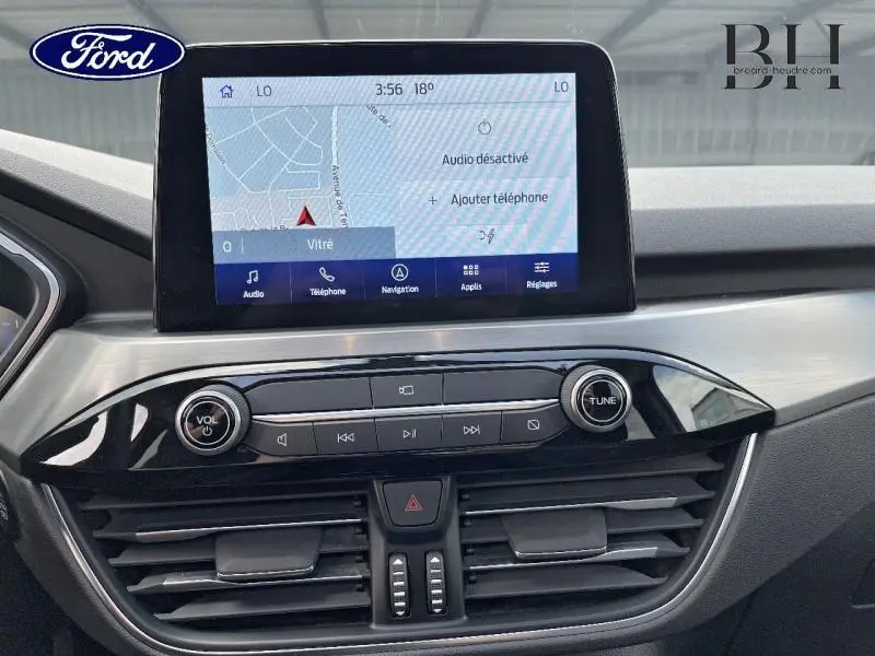 Vue rapprochée de la console centrale du Ford Kuga 2022 avec écran tactile affichant la navigation et commandes audio.