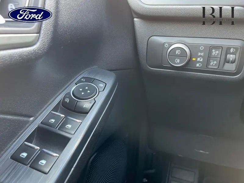 Vue rapprochée des commandes de vitres et des réglages d'éclairage côté gauche intérieur du Ford Kuga rouge Premium 2022.