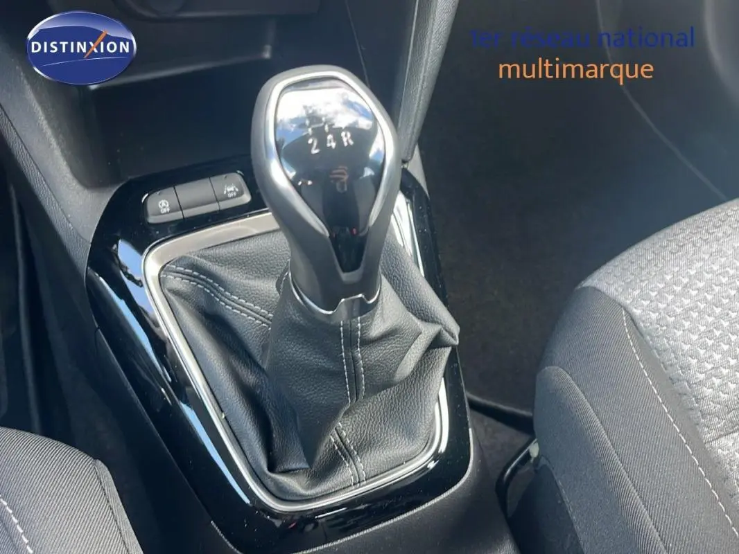 Gros plan sur le levier de vitesses manuel de l’Opel Corsa gris, avec coutures apparentes sur la soufflet en cuir noir.